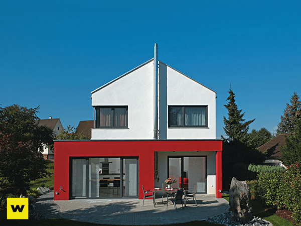 Modernes Einfamilienhaus mit Flachdach, roter Fassade und großer Terrasse im Garten.