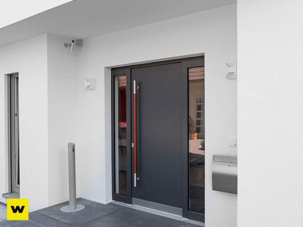 Moderne Haustür aus Aluminium mit Seitenteil in einem weißen Eingangsbereich eines Hauses.